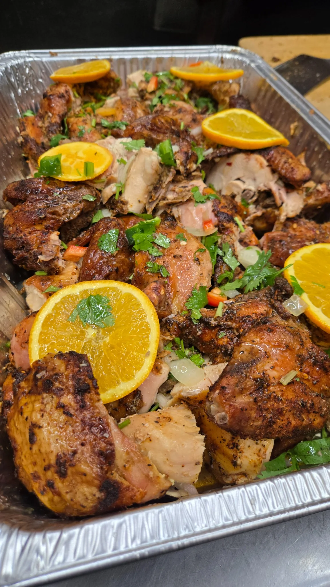 Catering tray with seasoned chicken pieces and orange garnish from Lugo's Lounge